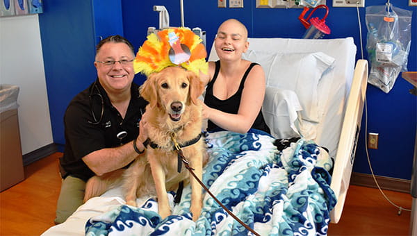 A pet therapy dog is visiting a hospital patient.