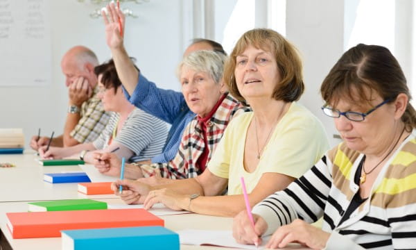 Participants at a BayCare Medicare Advantage seminar, seated at a table, with hands raised to engage in discussion.