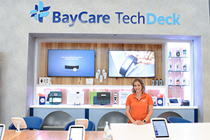 A certified health technology coach stands next to the BayCare TechDeck at the BayCare HealthHub in Largo. 