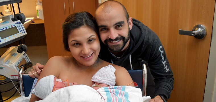 A couple using kangaroo care with two infants