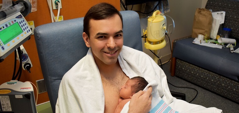 A man using kangaroo care with an infant