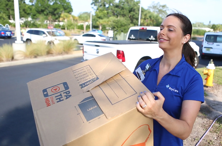 BayCare team member carries box of hygiene kits