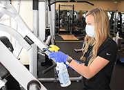 Fitness center staff member cleaning gym equipment