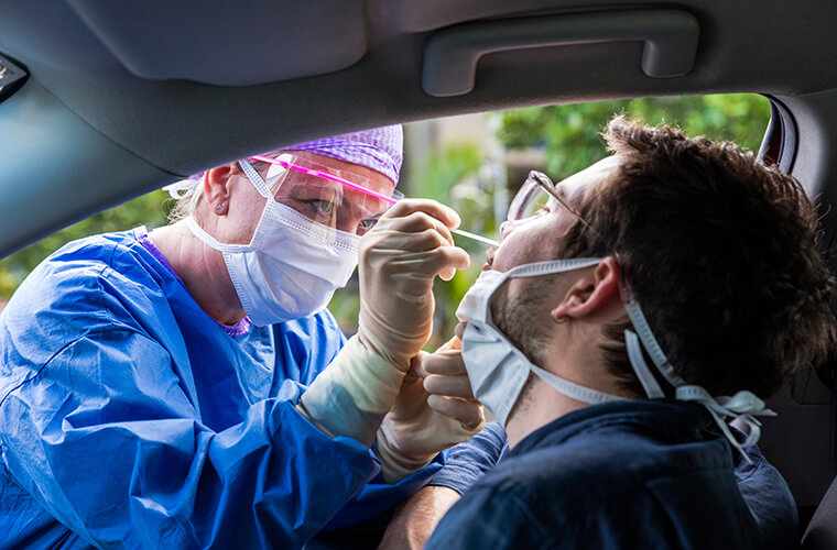 From inside patients car getting a nasal swab from a medial professional in PPE
