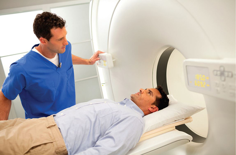 Male imaging technician working with patient using pet ct machine