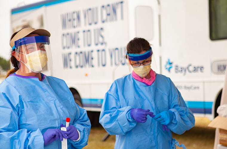 two men in PPE testing COVID samples