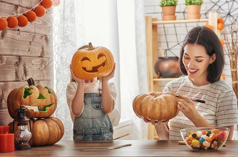 Child and mother decorating Halloween pumpkins