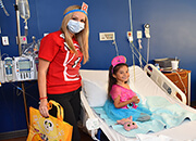 A child in a hospital with a person in costume next to the bed