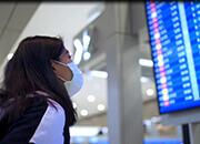 woman wearing a mask reviewing the airport arrival board