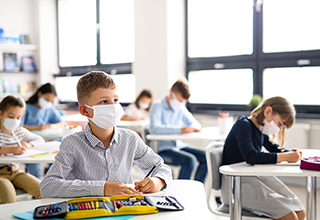 Children with face masks back at school during pandemic. 