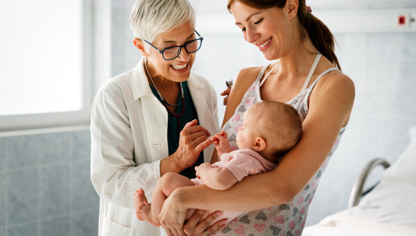 pediatrician and mother smiling holding her newborn baby