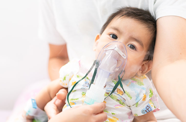 Sick toddler with respiratory illness using a nebulizer
