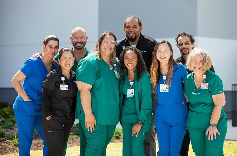 A diverse group of health care professionals in blue, black, and green scrubs.