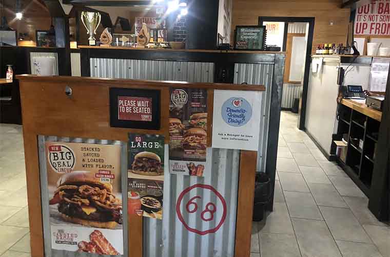A small sign that says Dementia-Friendly Dining is posted on a host stand in a restaurant.