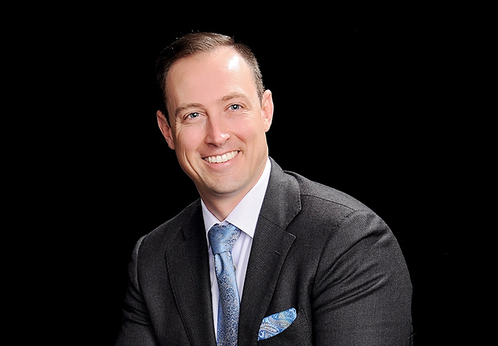 Professional portrait of Dr. Christopher Bucciarelli wearing a grey suit and light blue tie