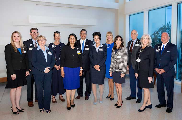 BayCare president and CEO Stephanie Conners stands in the lobby of the BayCare System Office surrounded by 11 members of the CEO Cabinet.