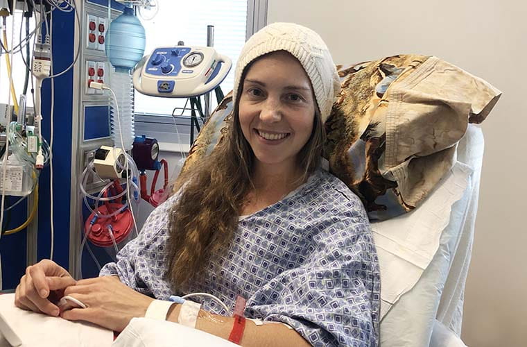 Female adult congenital heart defect patient sitting up and smiling in hospital bed after undergoing heart surgery at St. Joseph's Hospital in Tampa.