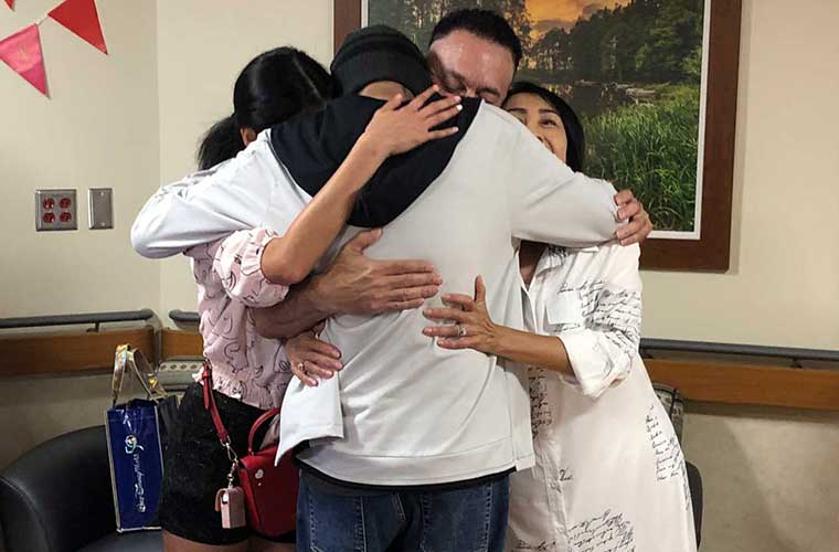 Aiya and his mother, father and sister share a group hug.