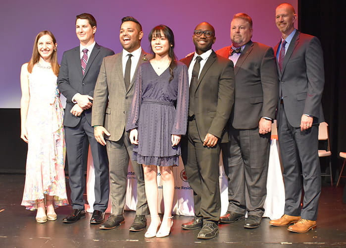 Graduating medical residents and faculty members pose for a photo at graduation ceremony.