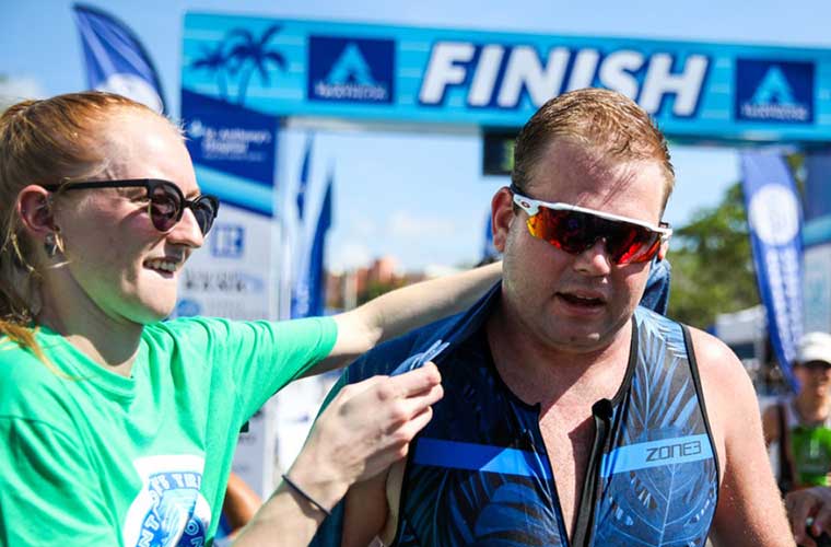 A volunteer provides a towel to comfort a triathlete at the end of the race.