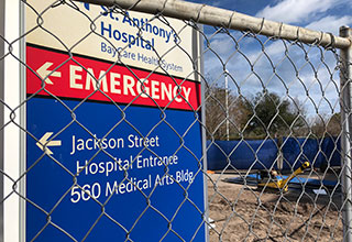 A close-up look at the hospital's directional signage located behind a fence where construction is underway.