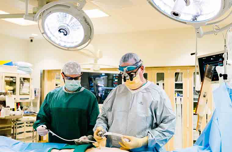 Two surgeons in an operating room standing over the operating table preparing to perform surgery.