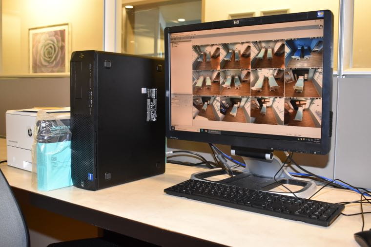 A monitoring station with a screen showing inside many patient rooms