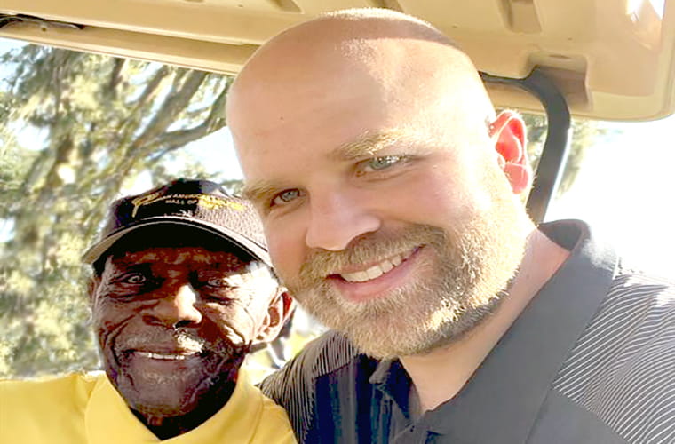 Two men take selfie photograph outdoors.