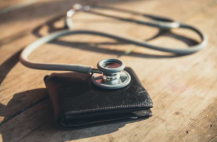 A silver stethoscope rests on top of a black wallet 