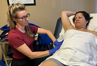 Shelby Green, a lymphedema therapist, uses a light circular touch to move lymphatic fluid near Odalmis Ricardo-Perez’s right surgical site during a treatment session.