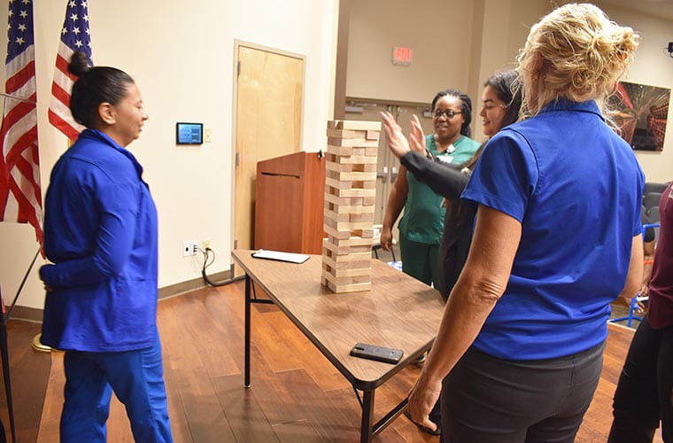 Team members stand around game. 