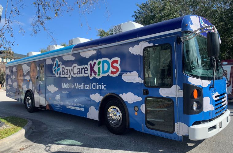 Mobile medical clinic bus with bright colors and BayCare Kids logo.