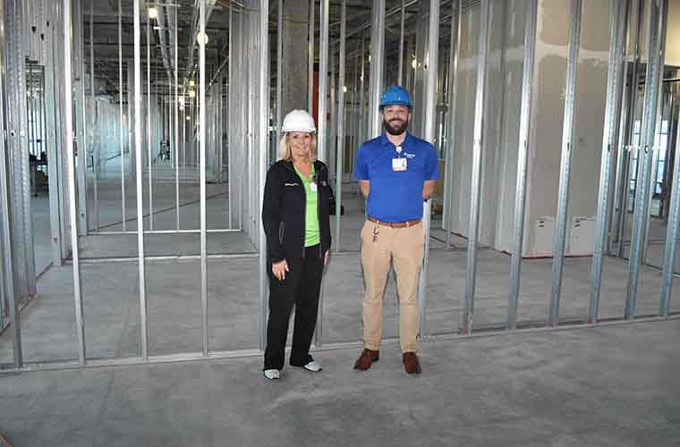 St. Joseph's Hospital-South operations director Michelle Landy and facilities manager Michael Lichtenstein wearing hard hats and standing in front of steel beams and unfinished floors of the observation unit.  