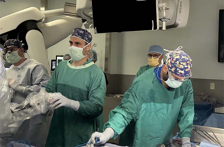 Four medical professionals prepare for surgery in a surgical suite.