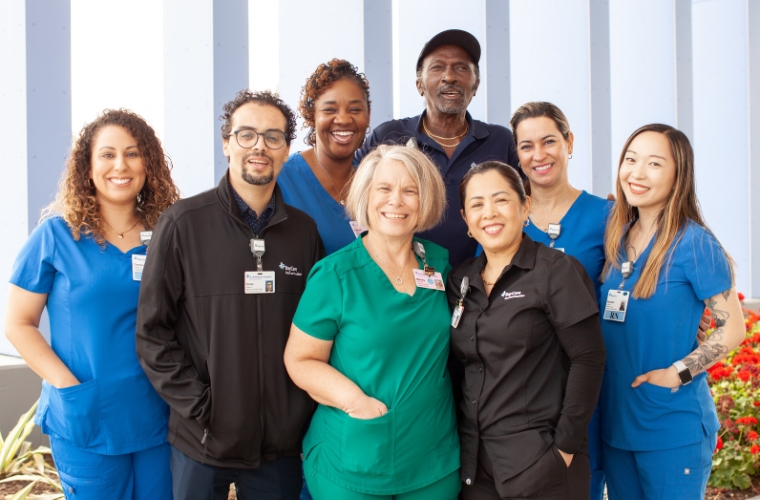 A diverse group of health care professionals in blue, black and green scrubs.