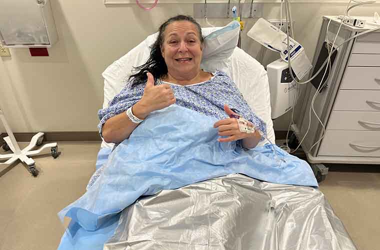A woman in a hospital bed giving the "thumbs up" sign. 