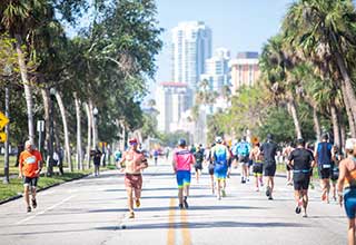 Many people in athletic company run along a large street in an athletic competition.