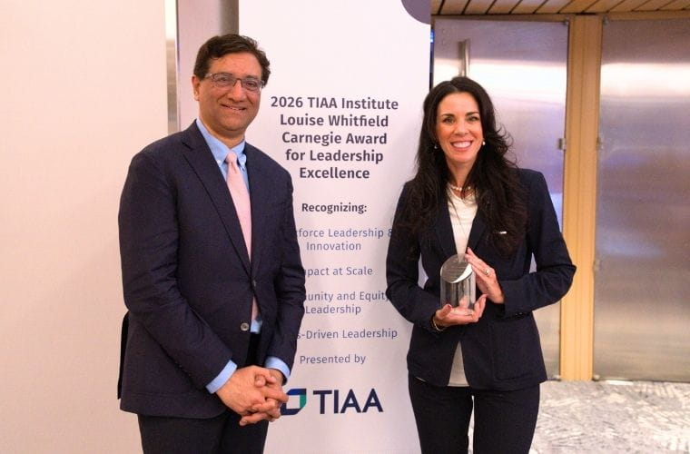 Stephanie Conners holds the Louise Whitfield Carnegie Award for Leadership Excellence while standing alongside Surya Kolluri with the TIAA Institute awards banner in the background.