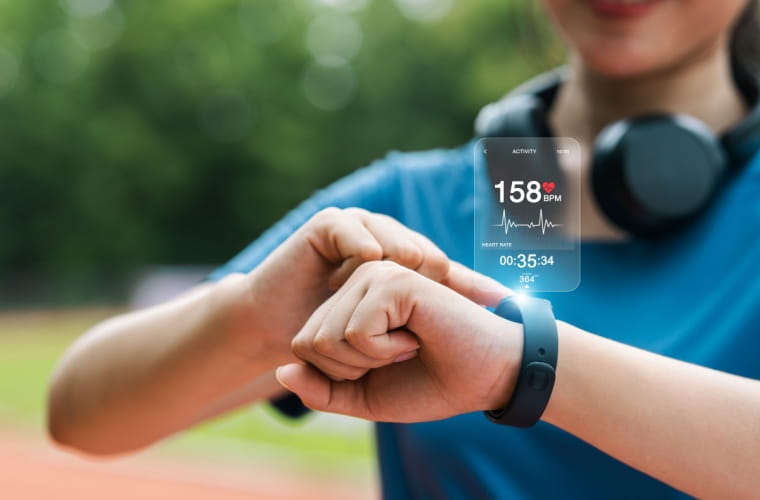 Person checking a fitness tracker showing a 158 bpm heart rate while exercising outdoors.