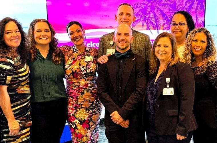 A group of BayCare Alliant Hospital team members standing together in front of a colorful event backdrop.