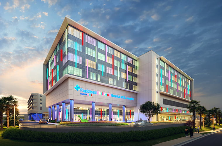 Rendering of the future Pagidipati Children’s Hospital at night, a modern multi‑story building with colorful window accents and a bright, open design.