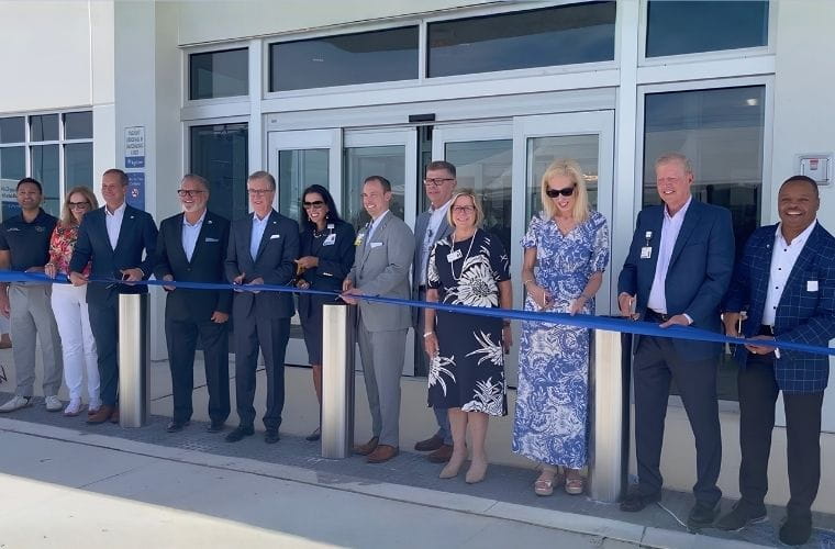 A group of BayCare leaders, board members and community leaders line up behind a long blue ribbon outside BayCare HealthHub (Manatee) main entrance as part of the grand opening celebration.