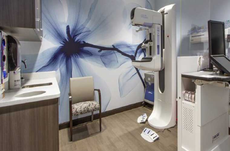 A room with blue walls and a large blue flower pained on one of the walls contains various medical equipment