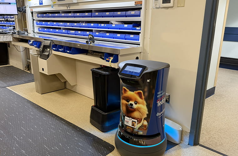 A robot with a Pomeranian image on it is plugged into a wall next to medical equipment.