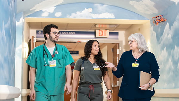 Two resident physicians walk through the hall with one of the program faculty.