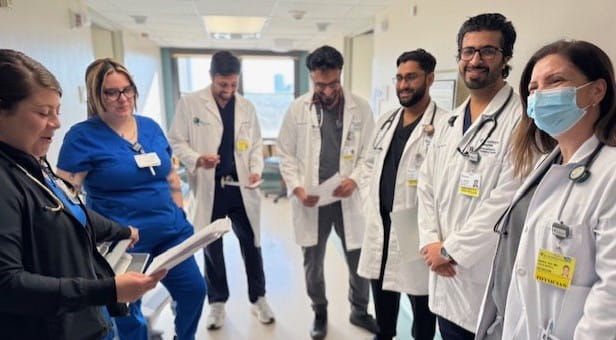 Faculty members standing together in a semi-circle in hospital hallway 