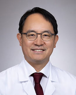 Headshot of Younqan Kim, PhD, MD in a lab coat