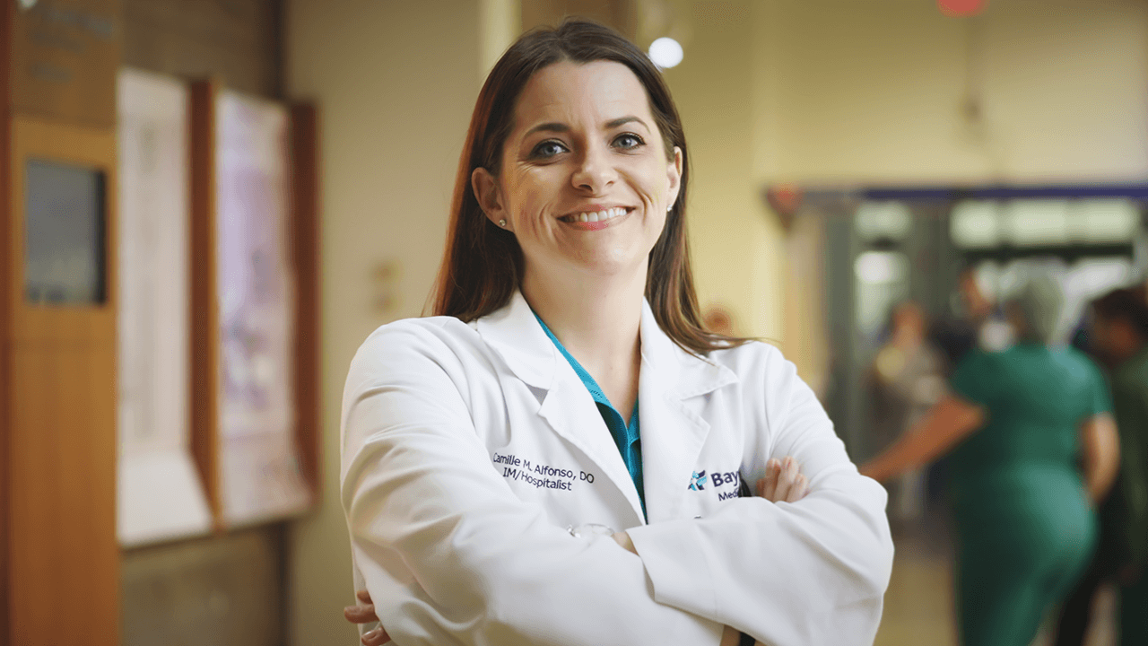 BayCare's Internal Medicine Residency Program at St. Joseph’s Hospital A female hospitalist at BayCare smiling with her arms crossed in a hospital setting.