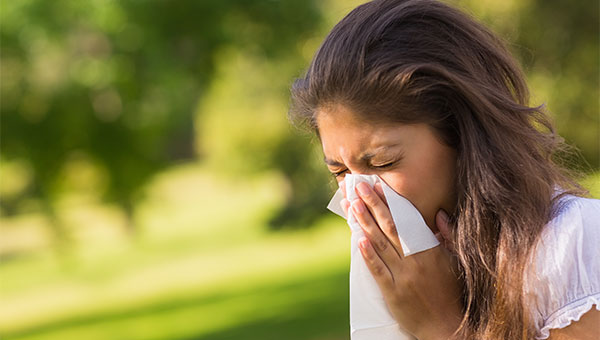 A woman is sneezing into a tissue.