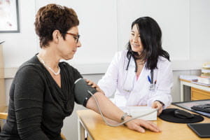 A woman is getting her blood pressure checked by a healthcare professional.